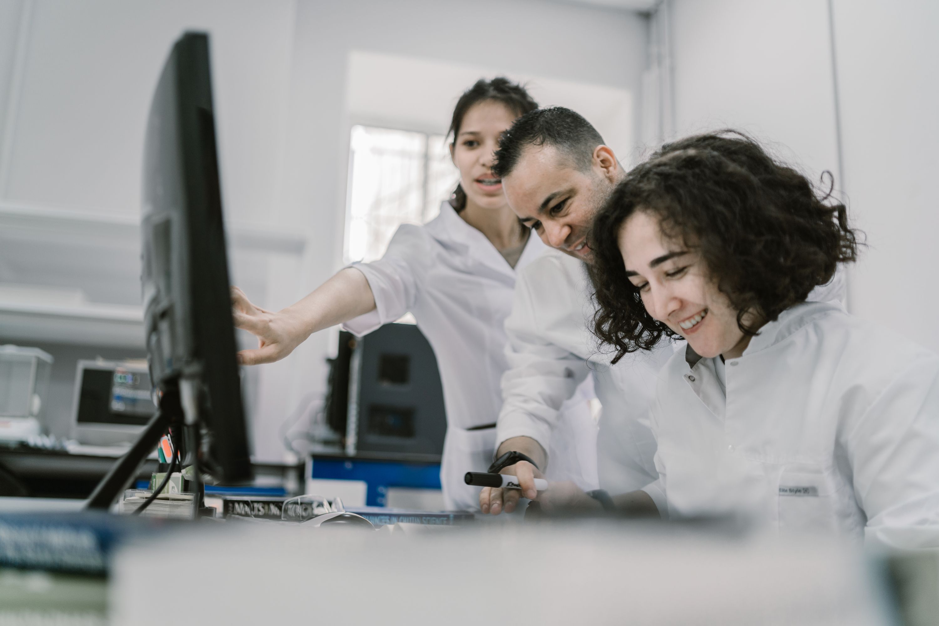 Illustrative stock photograph: white-coated scientists collaborating at a modern laboratory workstation