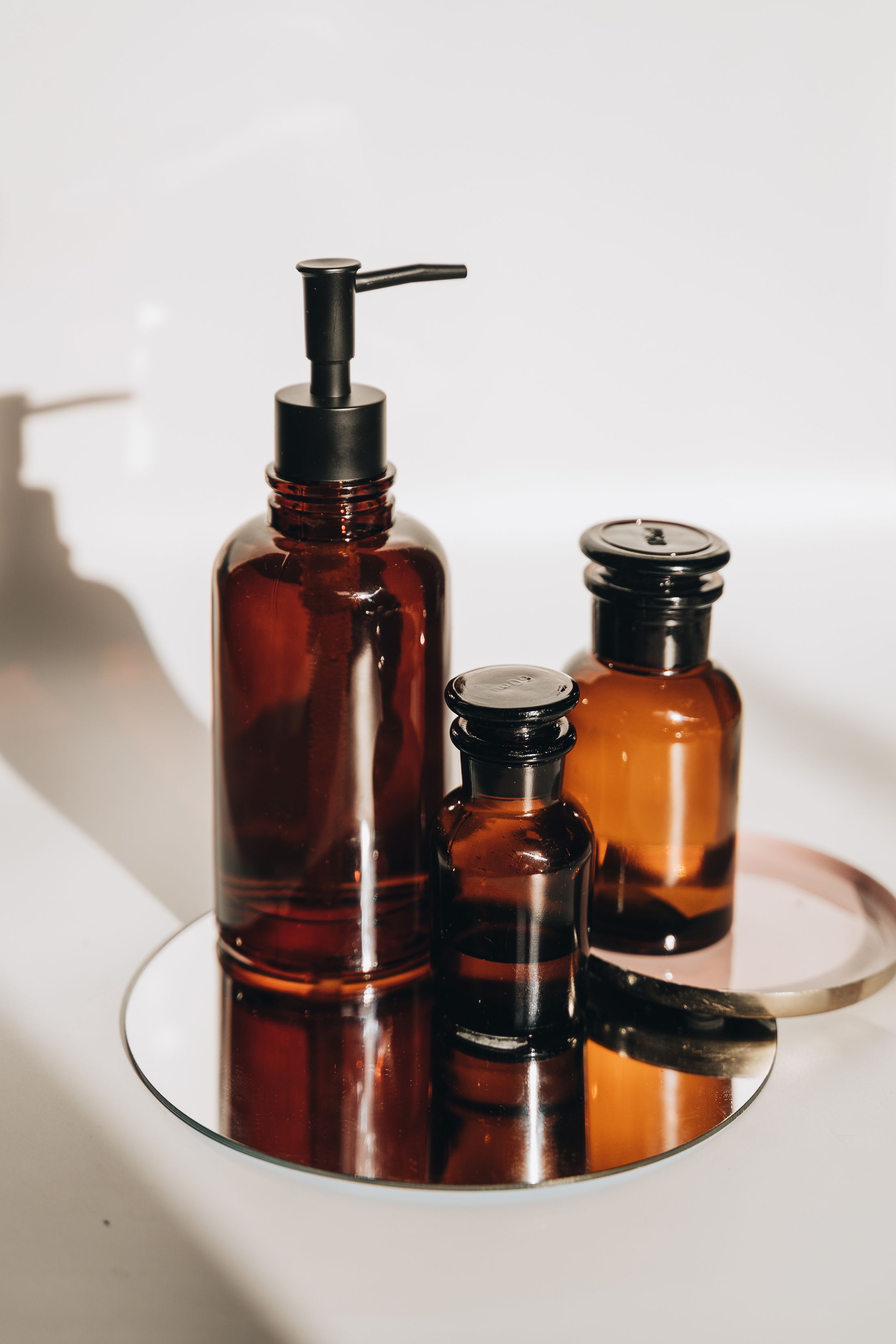 Clearly visible amber glass oil bottles and dispenser on a mirrored tray